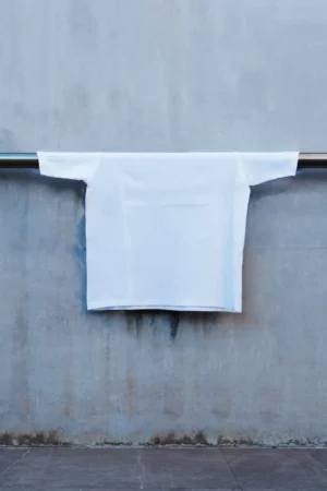 White t-shirt mockup placed on a metal bar in an industrial scene. Apparel and clothing mockup.