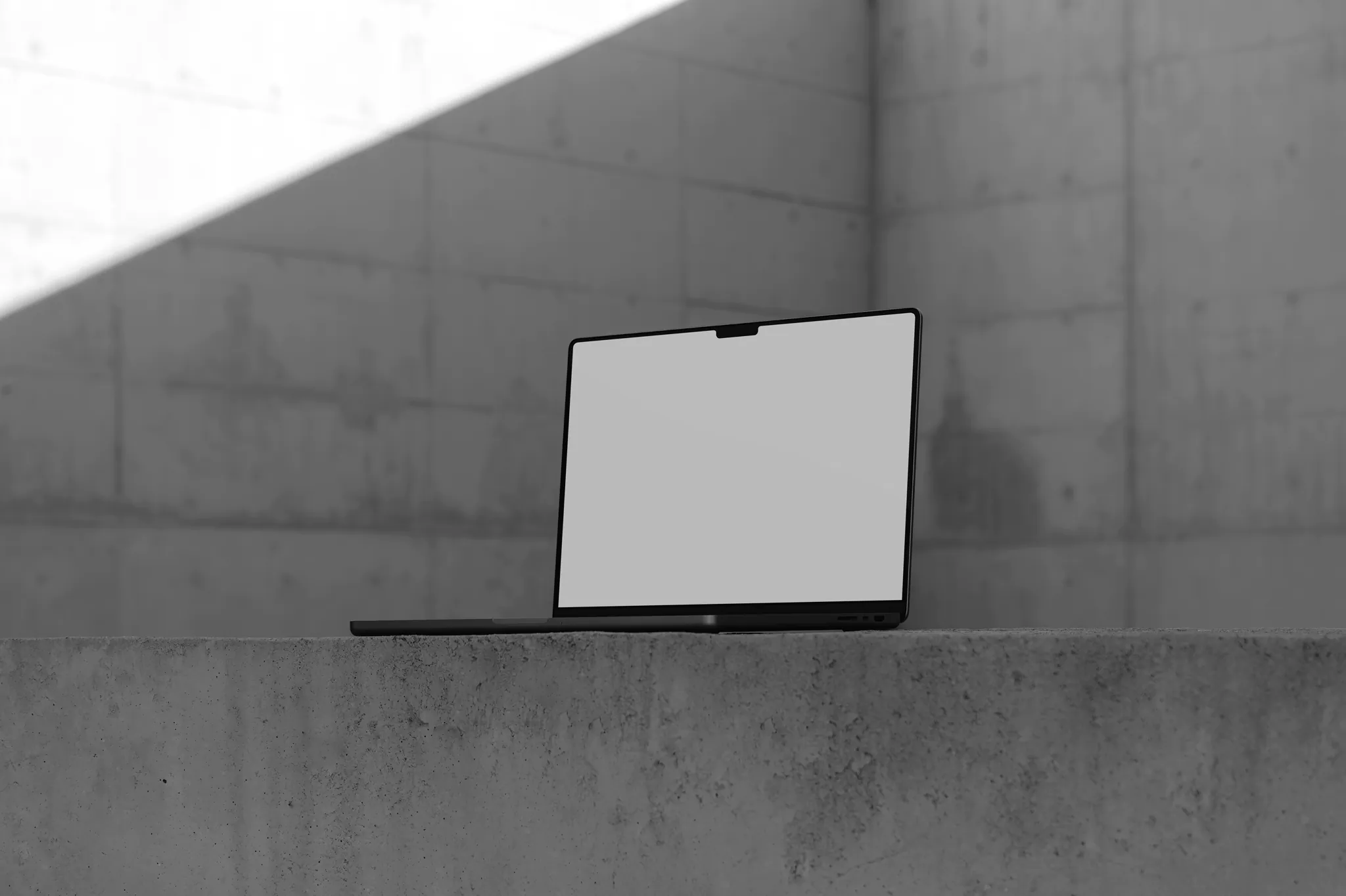 Macbook Pro mockup on top of a concrete surface in a concrete scene with real lights and shadows. Tech mockup.