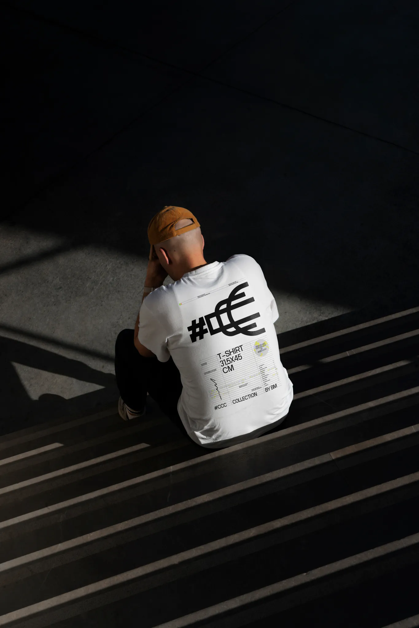 White t-shirt back PSD mockup. Man sitting on concrete stairs in a concrete scene wearing a t-shirt mockup. Fashion and apparel mockup.