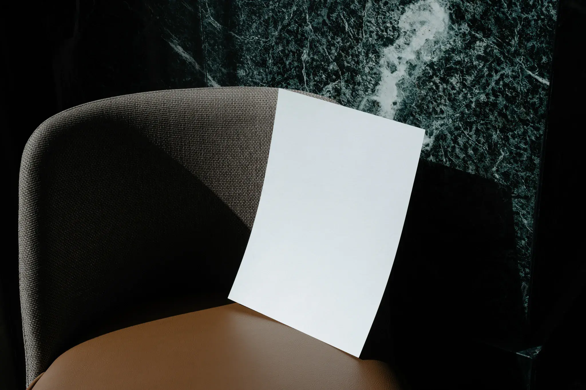 A Format PSD mockup placed on an elegant chair with a beautiful marble wall behind. Stationery mockup.