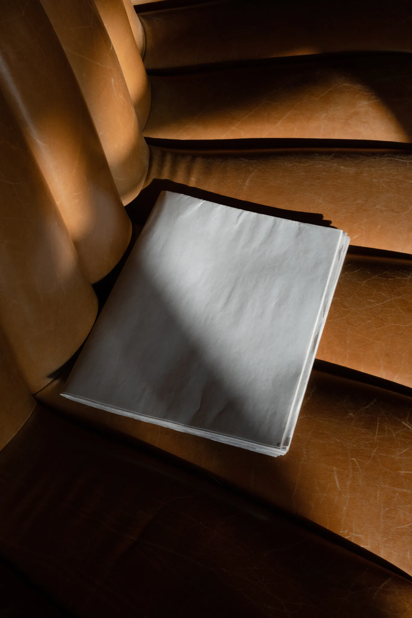 Newspaper format mockup on top of a brown leather couch. Editorial mockup.