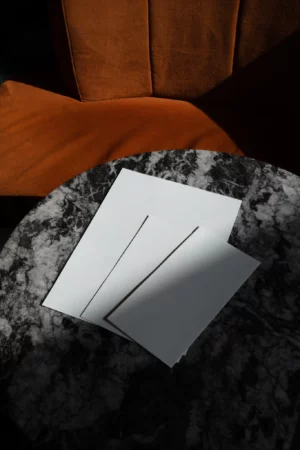 Stationery mockup over a fancy marble table next to an orange couch in restaurant. Branding mockup.