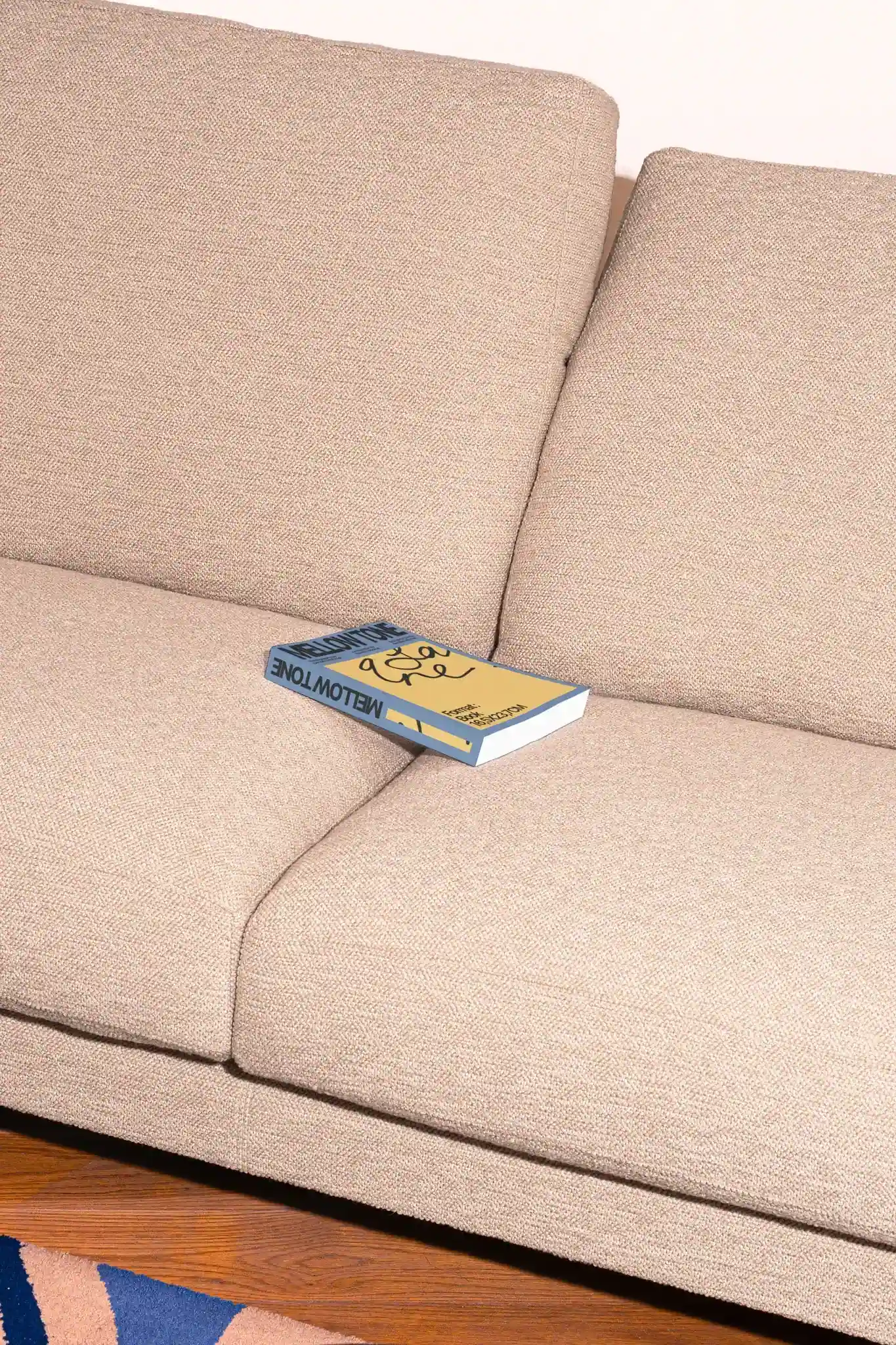 Soft cover book mockup laying on top of a fancy beige couch. Premium soft cover book mockup in a beautiful house interior. High quality book cover mockup.