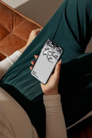 Female hand holding a high-quality iPhone mockup surrounded by designer's furniture. Premium iPhone mockup in a dream apartment