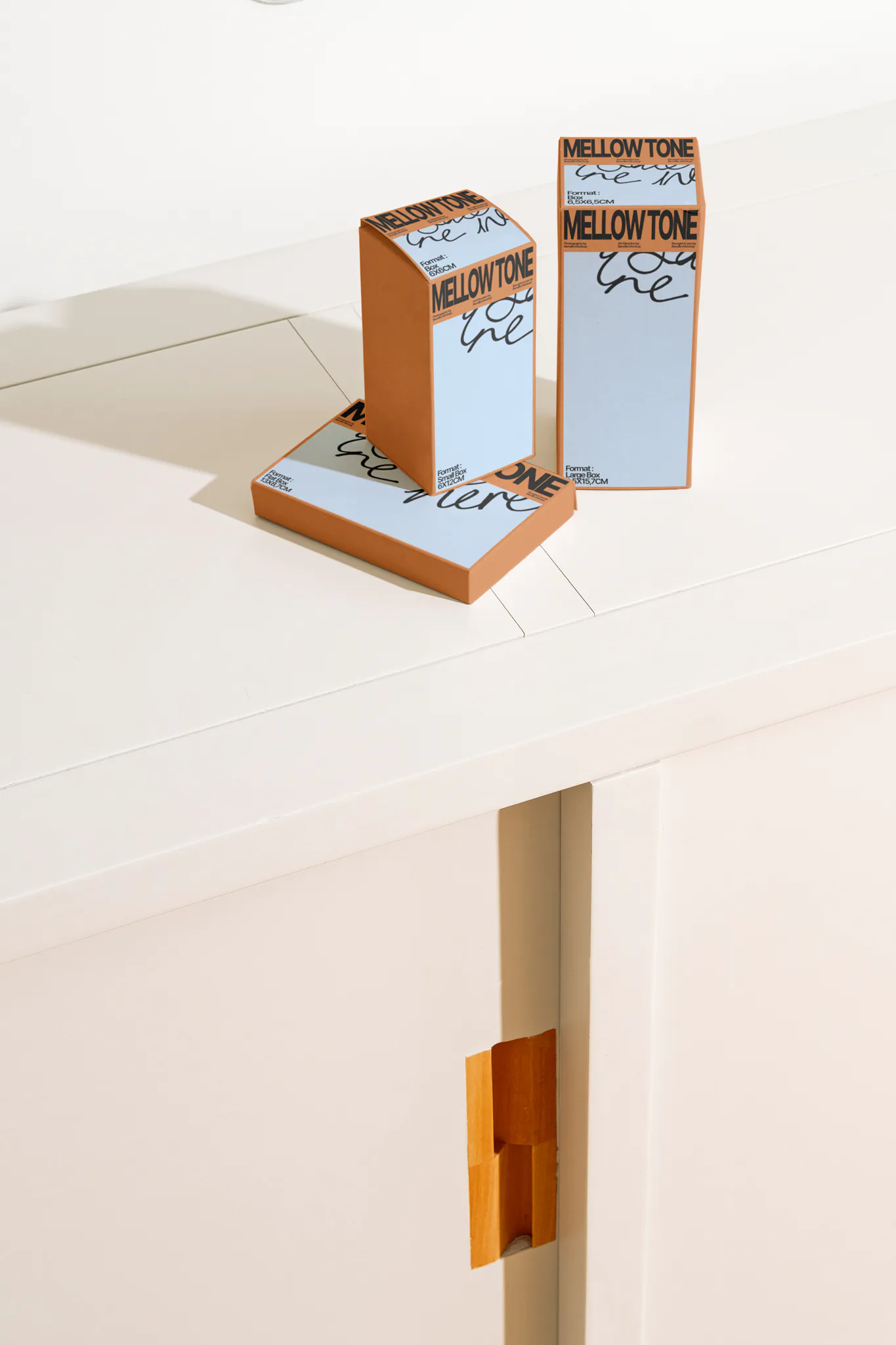 Box mockup laying on a white wooden surface. Piles of boxes mockup resting on each other with a beautiful background. Sophisticated packaging mockup laying on a wooden cabinet, mid-century inspired.