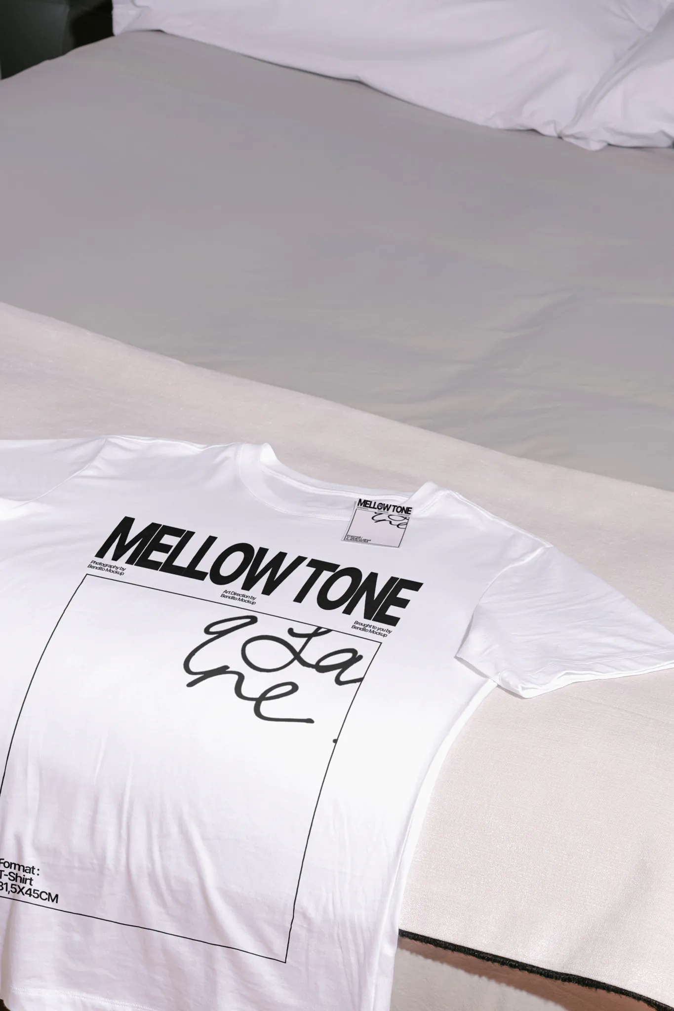 High-quality t-shirt mockup laying on a bed with white sheets. High-quality short sleeve t-shirt mockup resting on top of a blank. PSD mockup file of a white t-shirt