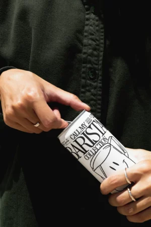 Aluminum can mockup being open by a woman, wearing black and modern clothes. PSD mockup file of a beer can, cold brew coffee can, beverage can, being open by a hand. Premium quality packaging mockup.