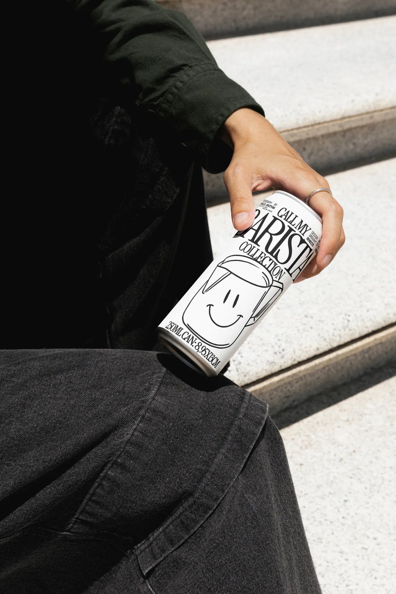 Aluminum can mockup being grabbed by a human hand, surrounded by urban background. The woman is wearing black clothes and grabs the can naturally. PSD mockup file, premium quality. Beverage mockup, cold brew coffee mockup, beer can mockup.