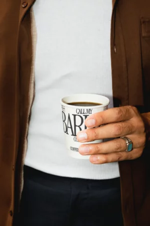 Hand holdind coffee cup mockup. Man holding a paper cup mockup, wearing modern clothes. Urban background, minimalist style. Tea cup mockup, white cup mockup, packaging mockup, drink mockup, high quality mockup, PSD file.