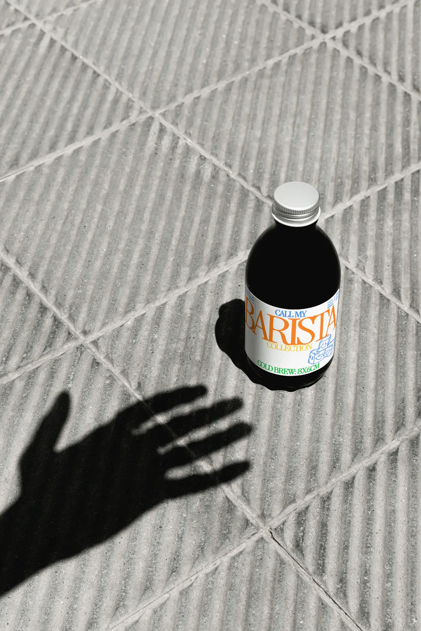 Cold brew coffee mockup laying on the street, concrete floor, surrounded by the shadow of a hand. Coffee bottle mockup, glass bottle mockup, coffee label mockup, liquor label mockup, packaging mockup, drink mockup, PSD file, high quality mockup.