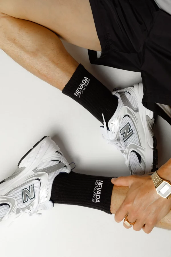 Legs of a male with black shorts wearing a pair of black socks mockup, black socks mockup, apparel mockup, fashion mockup, clothing mockup, PSD file.