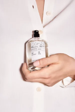 Woman with a white silk shirt holding a perfume bottle mockup. Perfume bottle mockup. Packaging mockup. Premium quality skin care mockup.