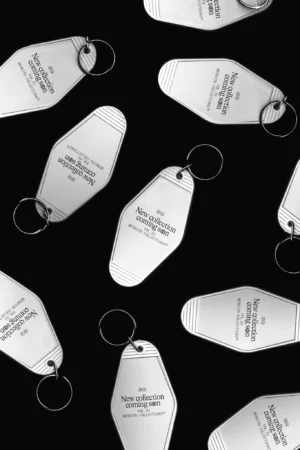 High-quality mockup with multiple keychains arranged randomly on a black background. Scanned keychain mockup. Vintage motel keychain mockup. PSD editable file.