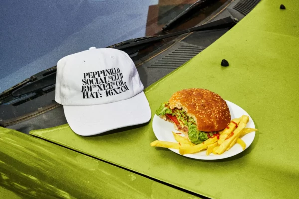 Hat mockup next to a plate with a hamburger and fries over the hood of a blue car in a burger restaurant parking. Clothing mockup. Hat PSD file. Cap mockup. Premium quality hat mockup. PSD premium editable file.