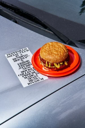 Menu mockup on the hood of a blue car in a take-away restaurant parking with a red plate with a burger next to it. Takeaway mockup. Restaurant menu PSD file. Print mockup. Fast food mockup. High-quality menu mockup. Burger PSD high-quality editable file.