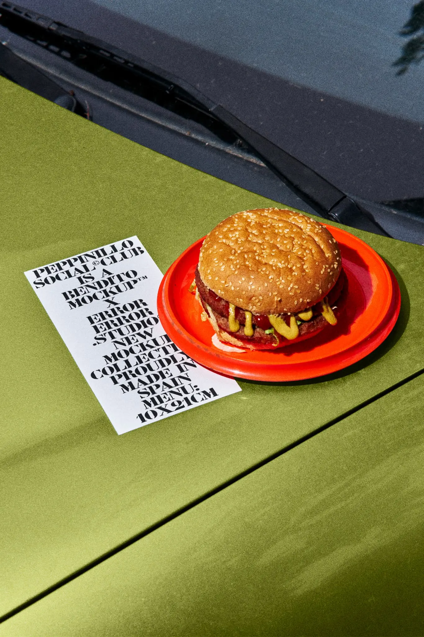 Menu mockup on the hood of a blue car in a take-away restaurant parking with a red plate with a burger next to it. Takeaway mockup. Restaurant menu PSD file. Print mockup. Fast food mockup. High-quality menu mockup. Burger PSD high-quality editable file.