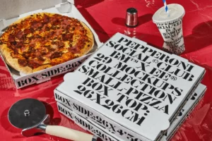 Aesthetic mockup of a pile of pizza boxes on a fast food restaurant table next to a pizza. Food mockup. Packaging mockup for italian restaurant. High quality PSD file mockup with editable pizza packaging for your brand.