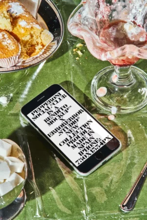 Aesthetic iPhone mockup on a green table cloth full of desserts in a fast food restaurant. Device mockup. iPhone PSD file. High-quality device mockup. Premium quality iPhone mockup.