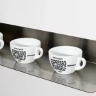 Espresso Yourself coffee cups arranged on a metal shelf