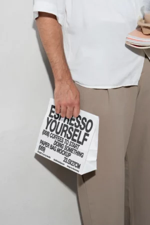 Person holding an Espresso Yourself paper bag mockup