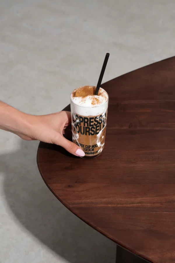Color Version: Hand holding an Espresso Yourself cup with a frothy coffee drink