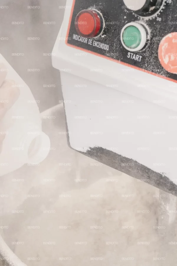 Zoom in of water being poured into a dough mixer in a bakery setting.