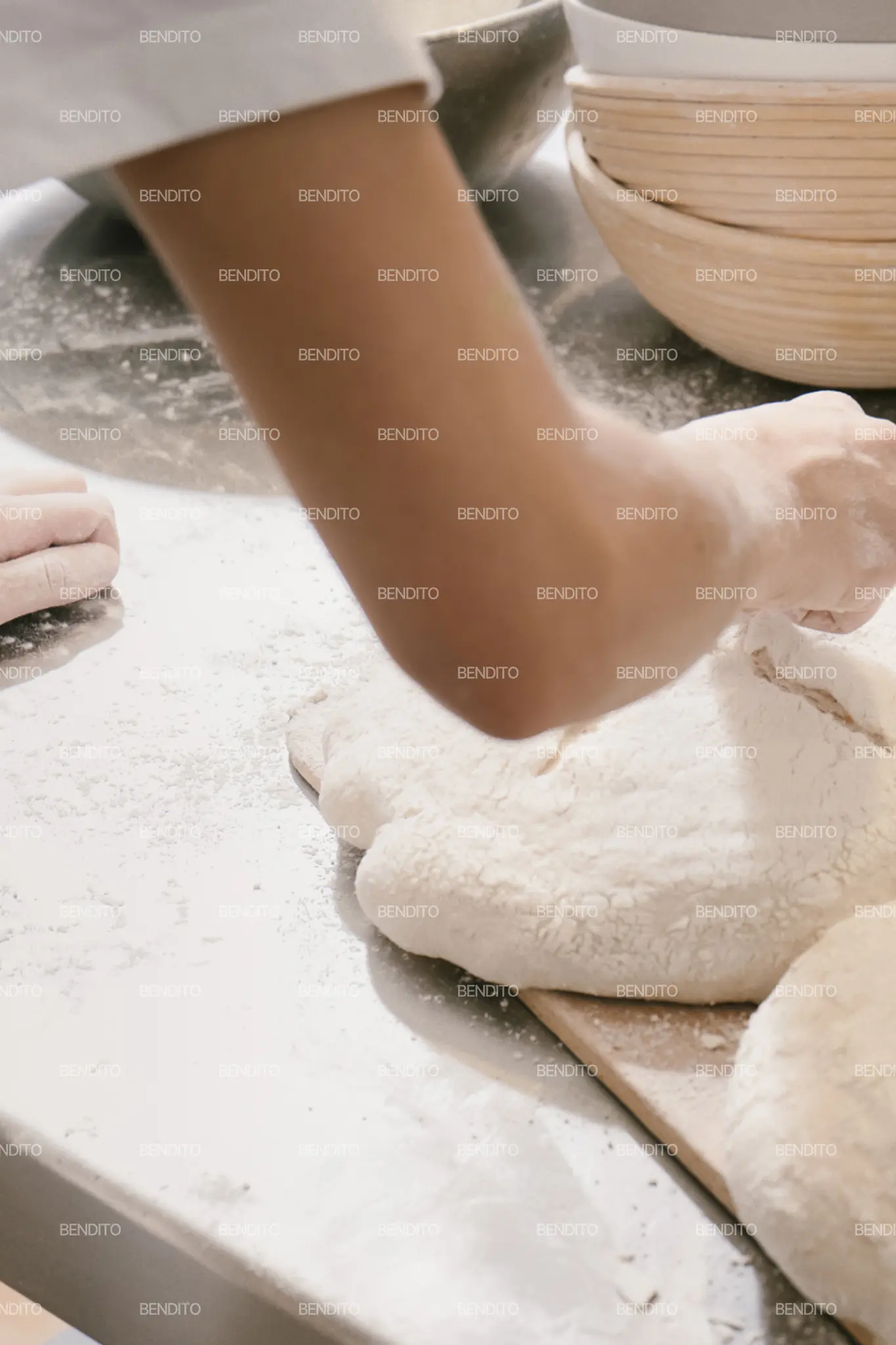Zoom in of a baker preparing artisan bread dough on a floured tray in a bakery.