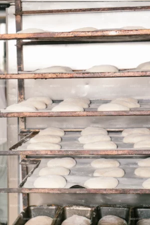 Rows of proofing dough placed on metal bakery racks ready for baking.