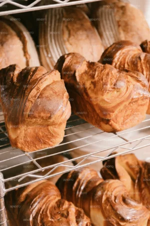 Freshly baked artisan bread loaves cooling on racks in a bakery setting.