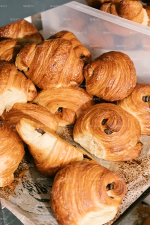 Golden chocolate croissants displayed fresh from the oven in a bakery setting.