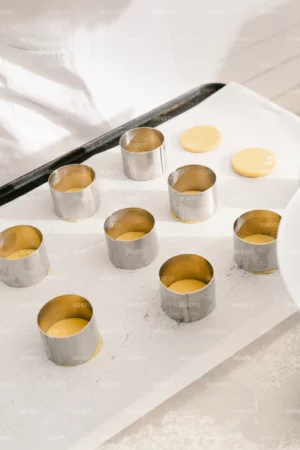Pastry dough circles placed in metal molds ready for baking.