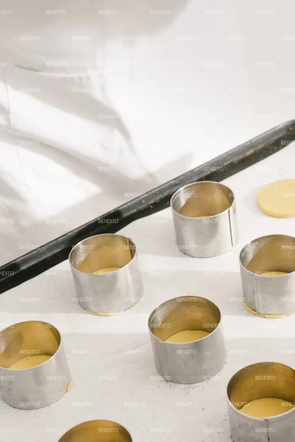 Zoom in of pastry dough circles placed in metal molds ready for baking.