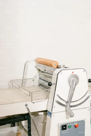 An industrial rolling machine for preparing dough in a professional bakery.