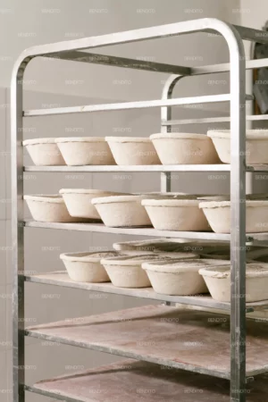 Metal rack holding proofing dough loaves in traditional baskets.