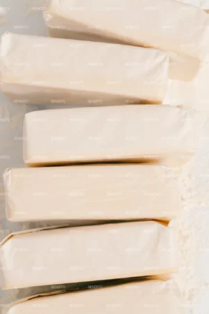 A stack of wrapped butter bars placed on a floured surface captured from above.