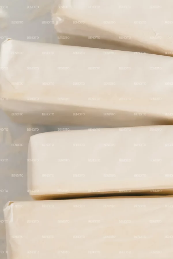 Zoom in of a stack of wrapped butter bars placed on a floured surface captured from above.