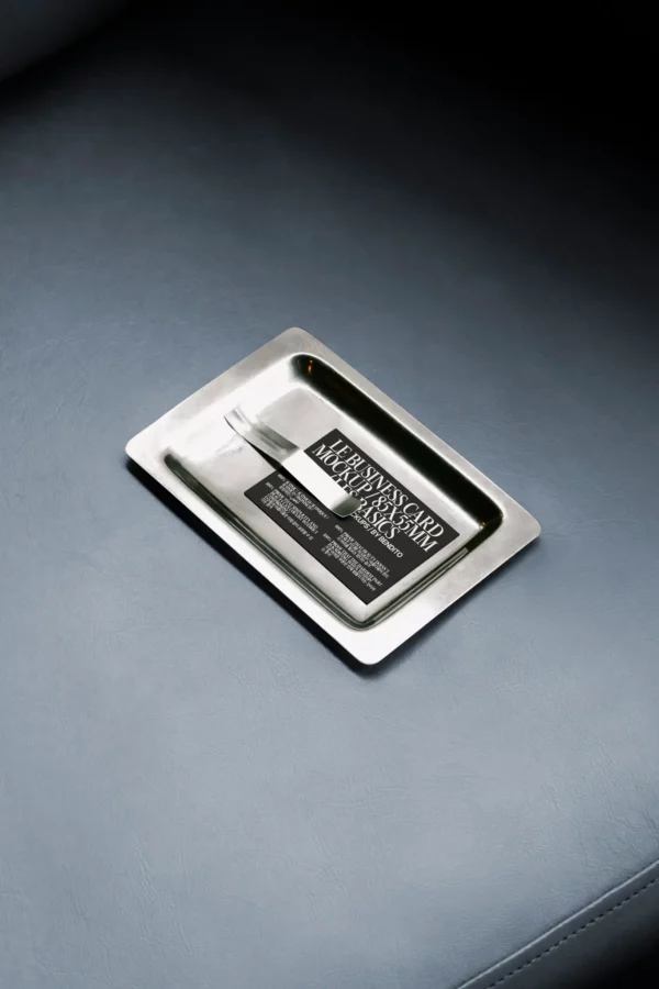 Color Version: A business card mockup placed on a reflective metal tray, resting on a leather surface.