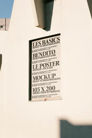 A framed poster mockup displayed on an architectural wall with sunlight creating structured highlights and shadows.