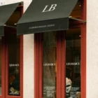 A black awning mockup shading a café entrance with soft shadows and strong structural framing.