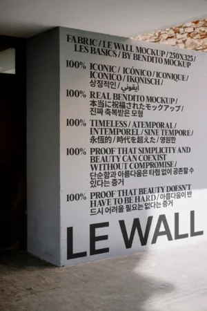 A mockup of a blank white wall with a wooden floor in a well-lit room.