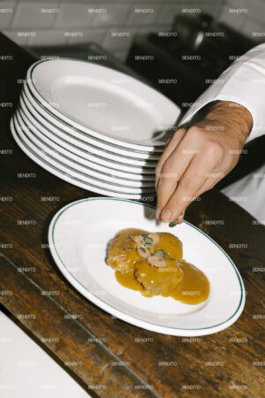 Chef plating a gourmet dish with sauce.