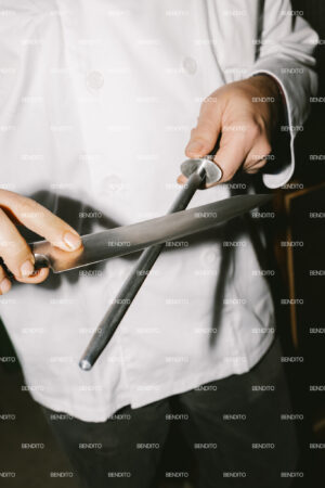 Chef sharpening a knife with a honing steel.