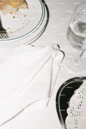 Restaurant table setting with white plates cutlery and a glass of water.