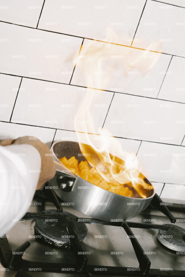 Tight crop of flames rising from a pan on a gas stove.