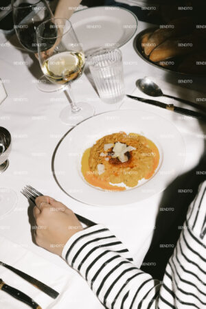 Saffron risotto plated at a restaurant table with wine and bread.