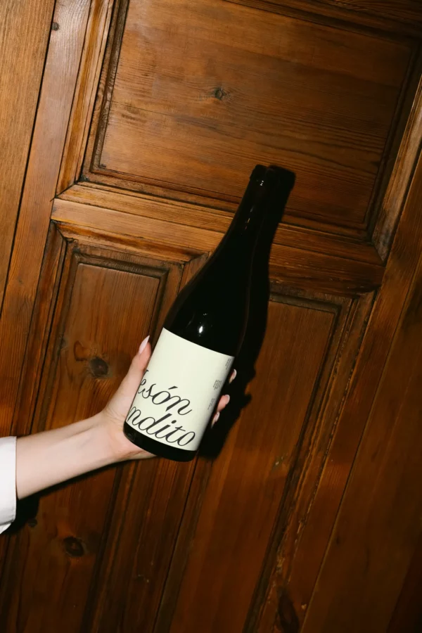 Color Version: Mockup of a wine bottle with a blank label held against a wooden wall. Ideal for rustic wine branding presentations.