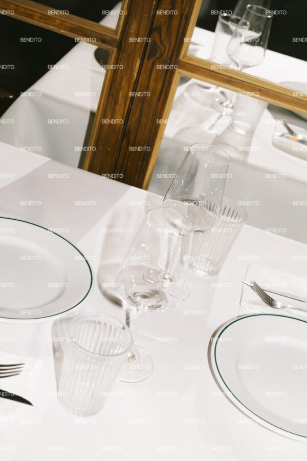 Zoomed-in view of a minimalist tableware arrangement with empty plates and wine glasses.