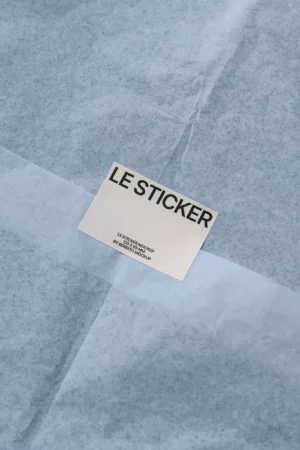 Simple sticker mockup placed on light blue tissue paper.