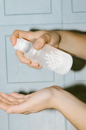 A plastic bottle filled with liquid soap placed against a neutral background.