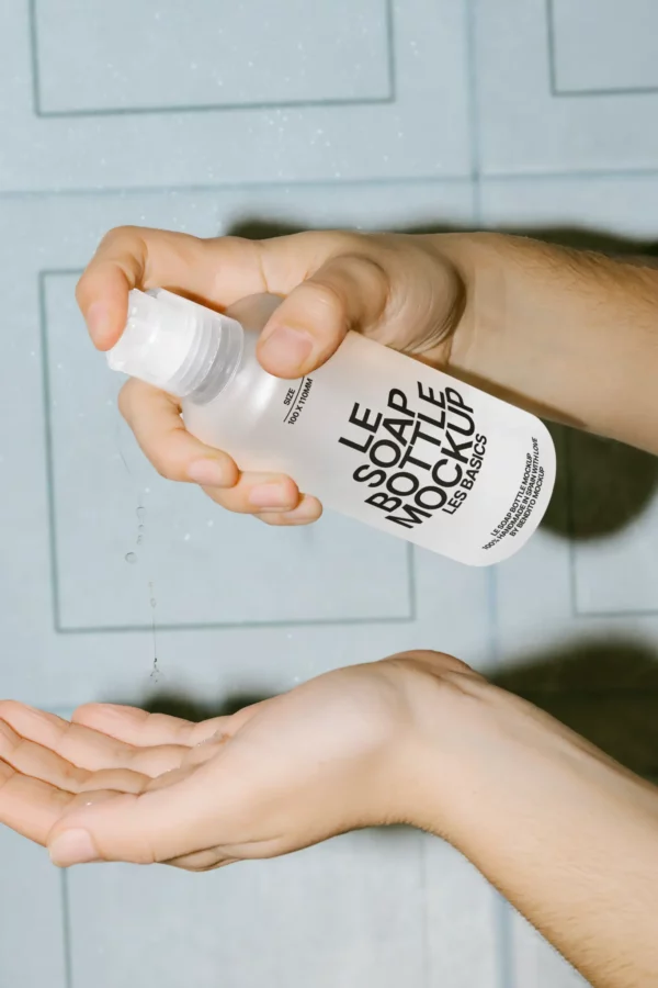 Handheld soap pump bottle mockup in action, with minimalist black text on a frosted container—ideal for branding personal care or hygiene products.